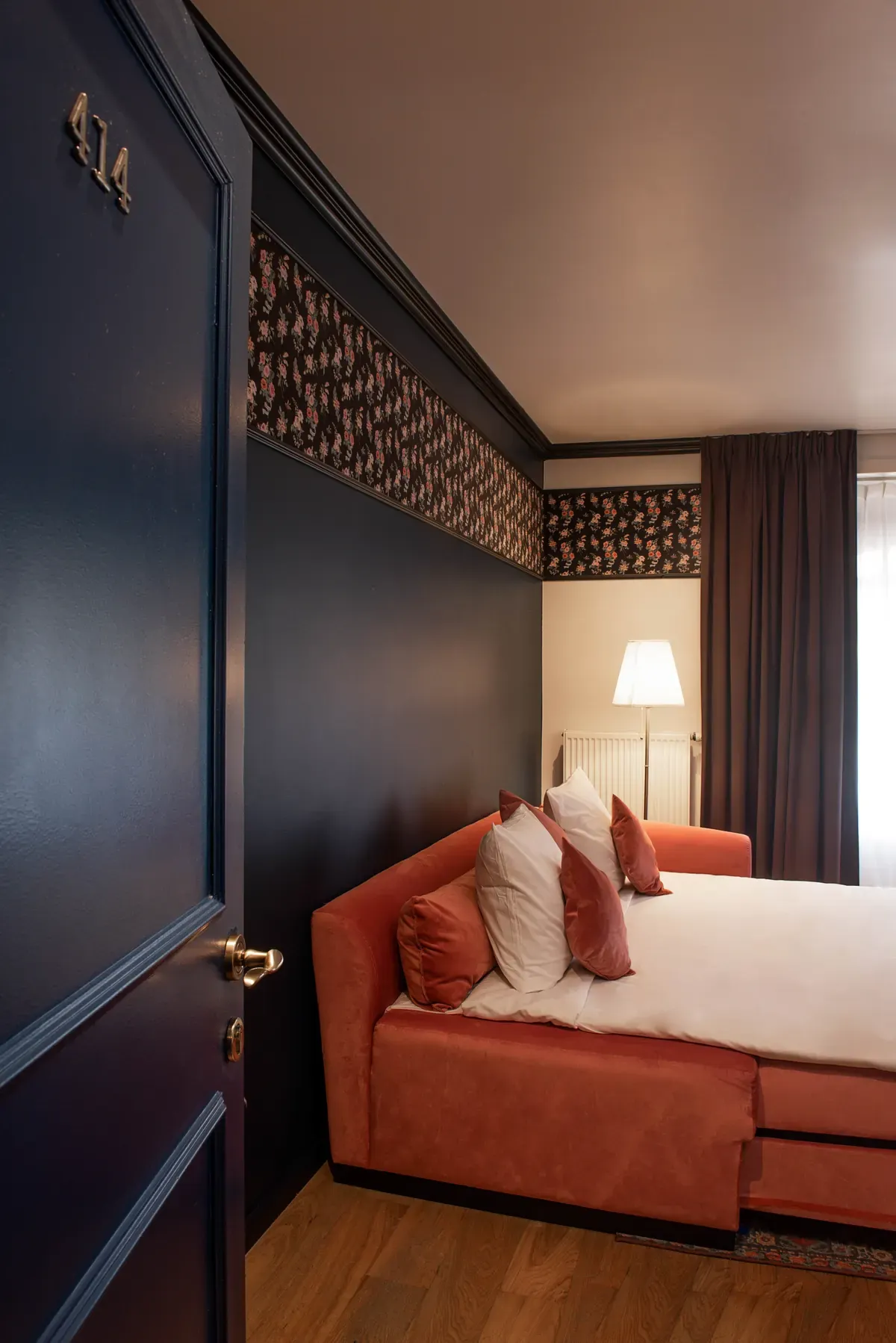Beds in the family room, floral wallpaper and velvet headboard