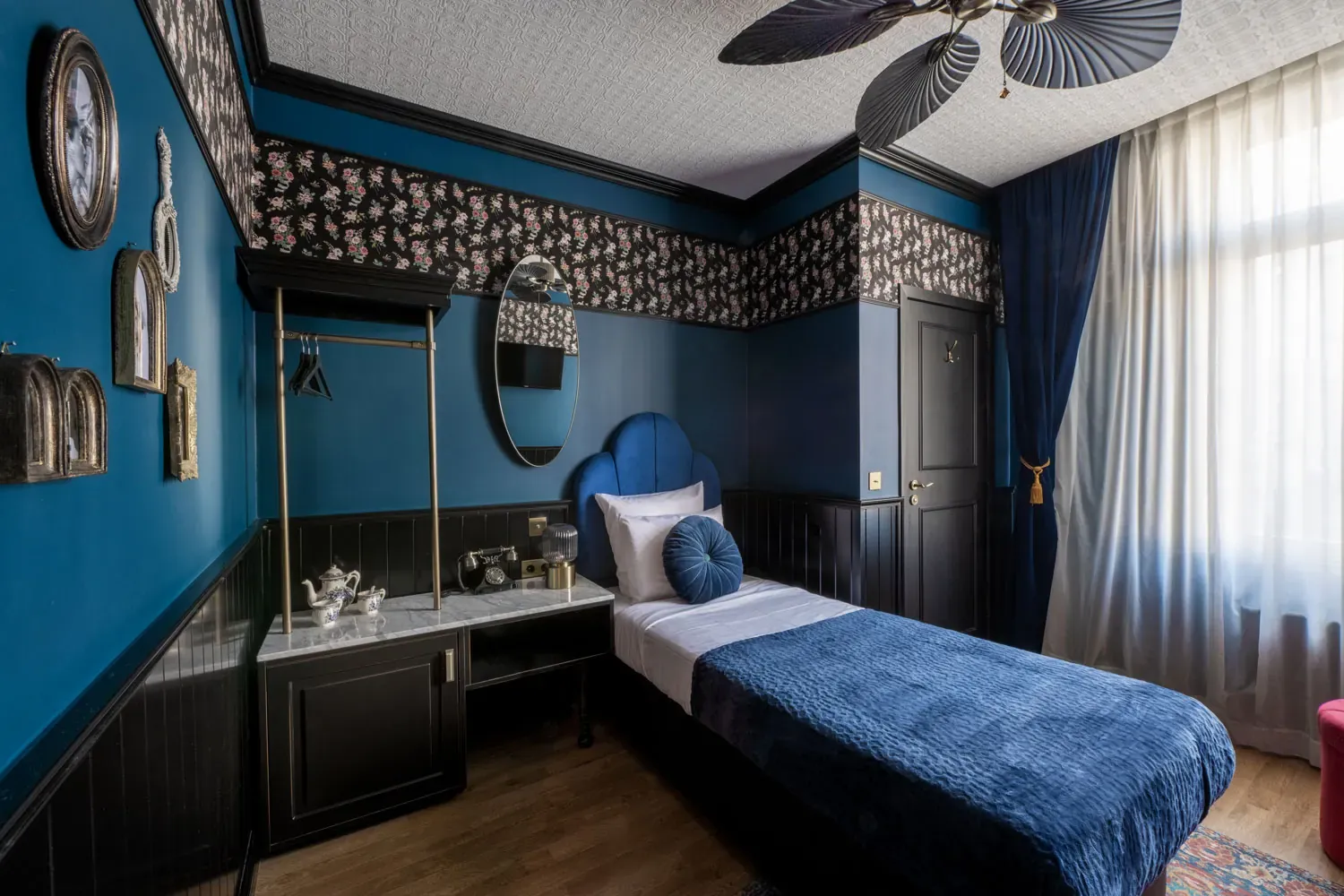Single room at Craves Hotel with single bed, blue velvet and floral wallpaper
