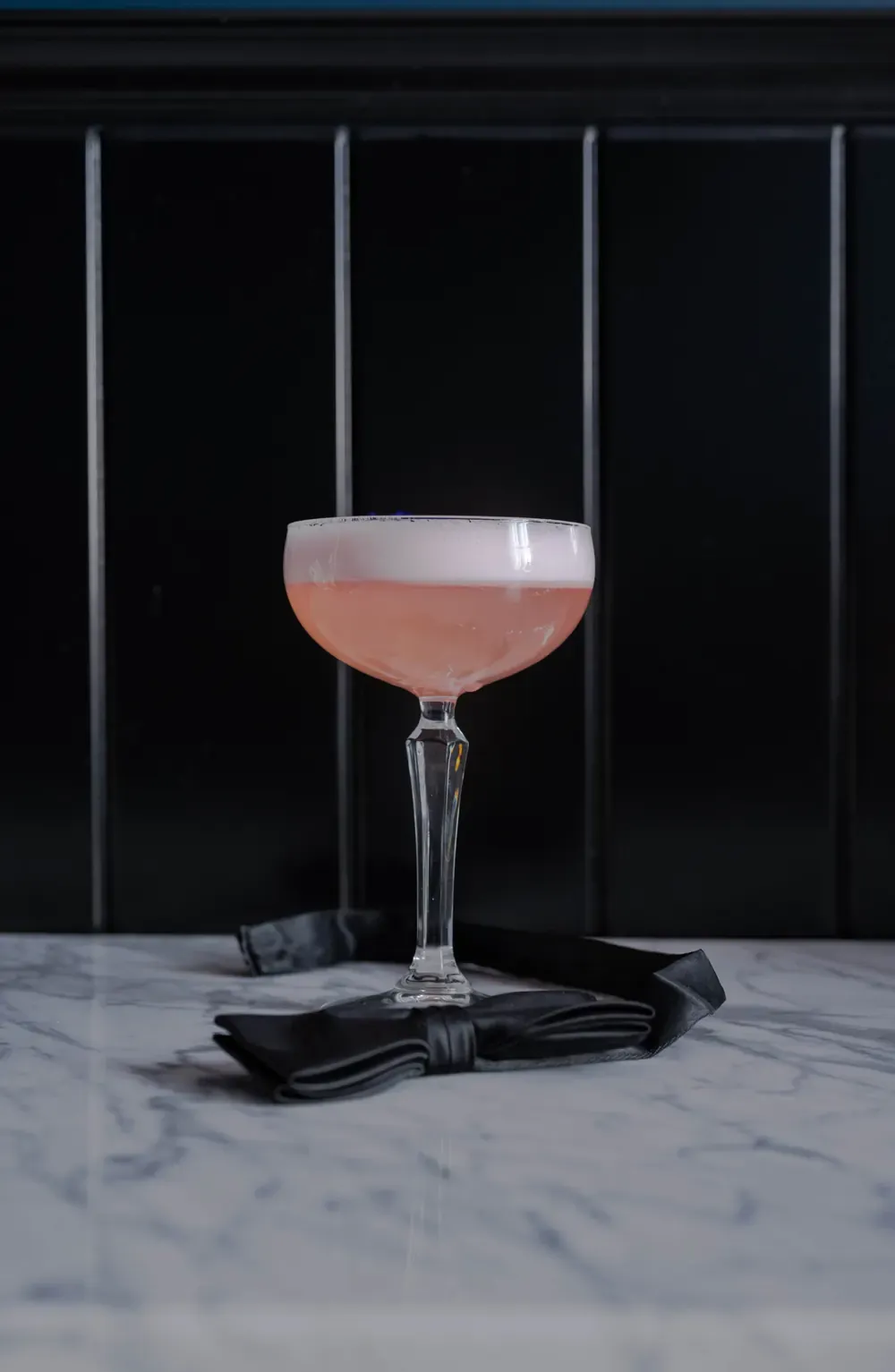 Roze cocktail in een coupeglas op marmer