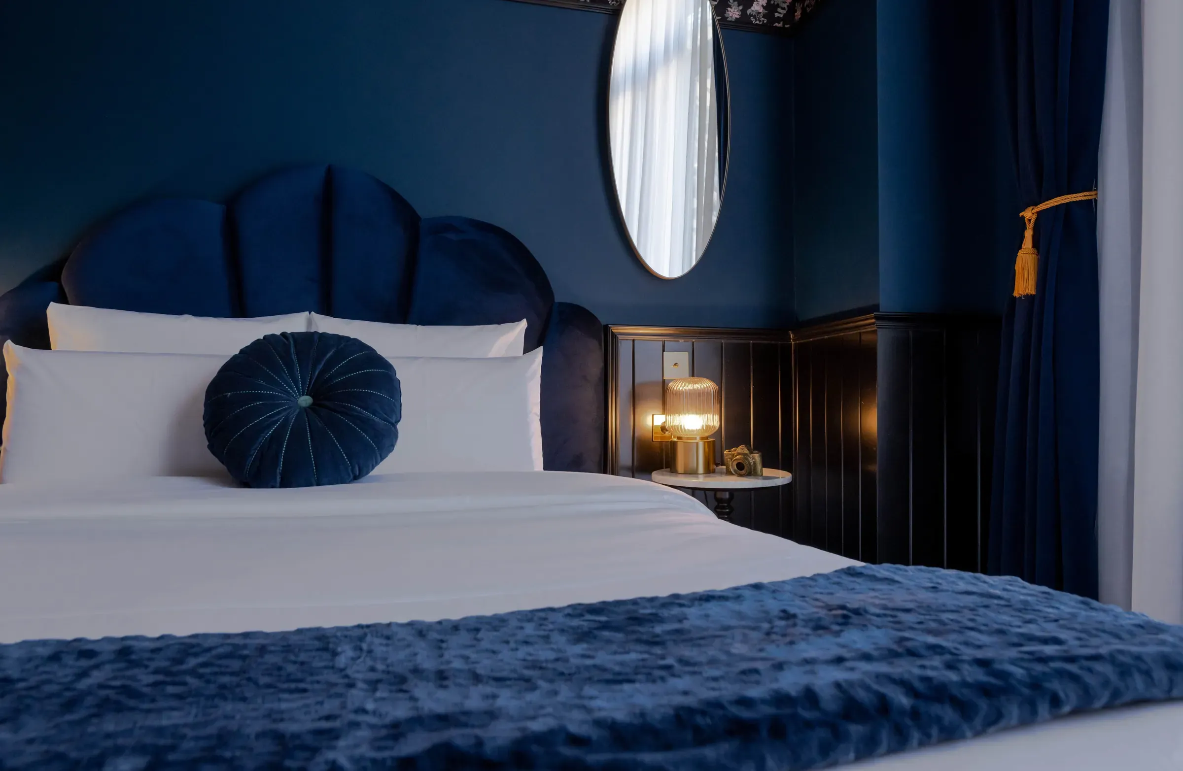 Room at Craves Hotel in Brussels: blue velvet headboard, round cushion and oval mirror