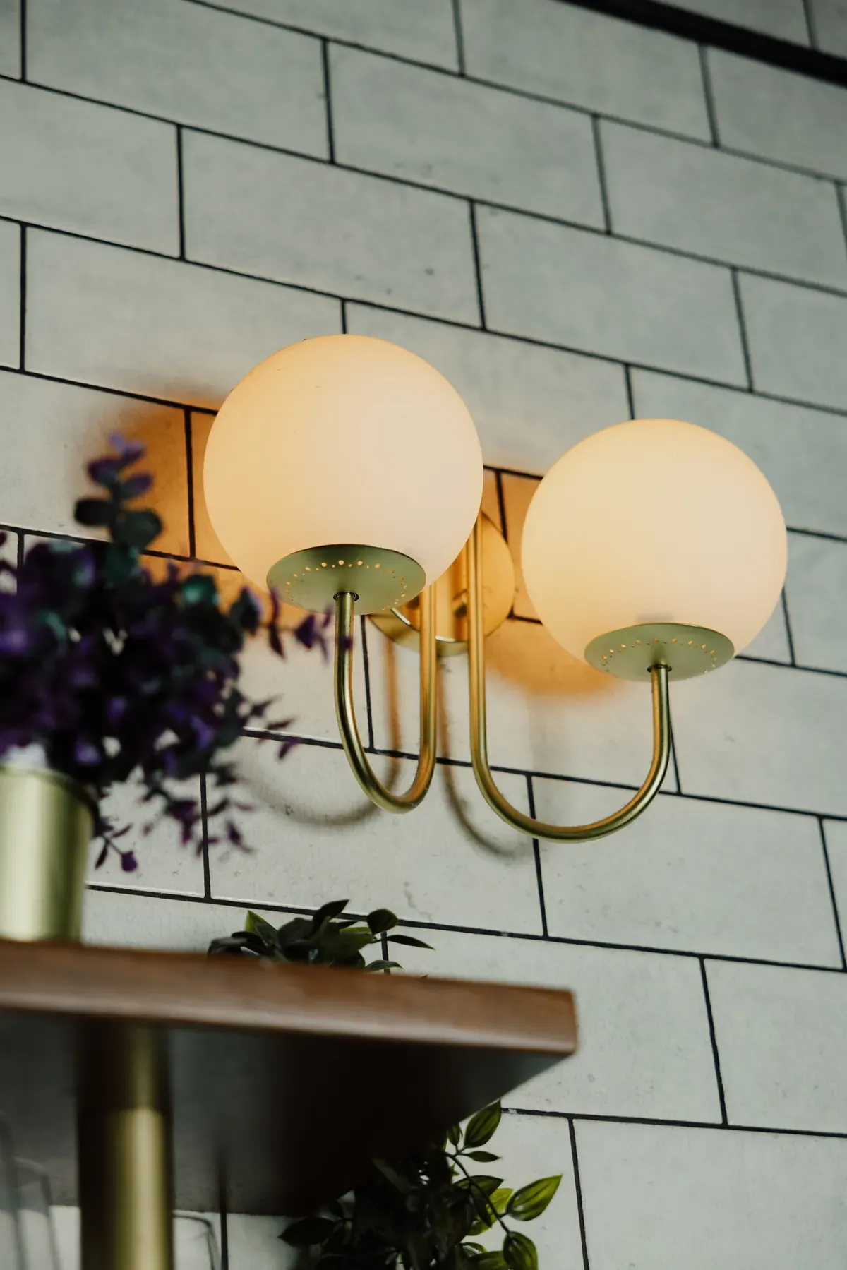 Brass wall light on the white tiles of Le Conteur