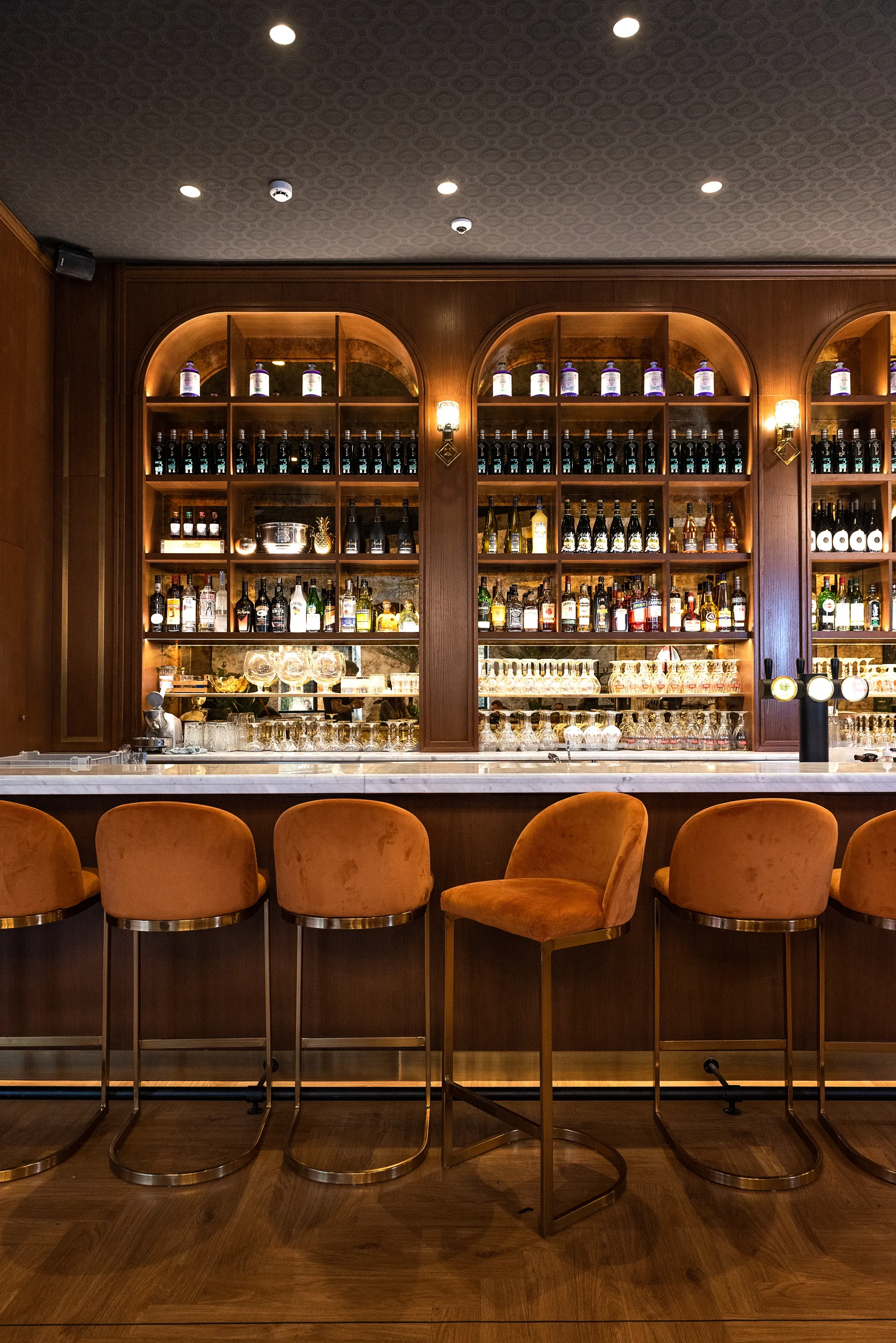 The bar at Le Conteur restaurant, orange stools and shelves of bottles