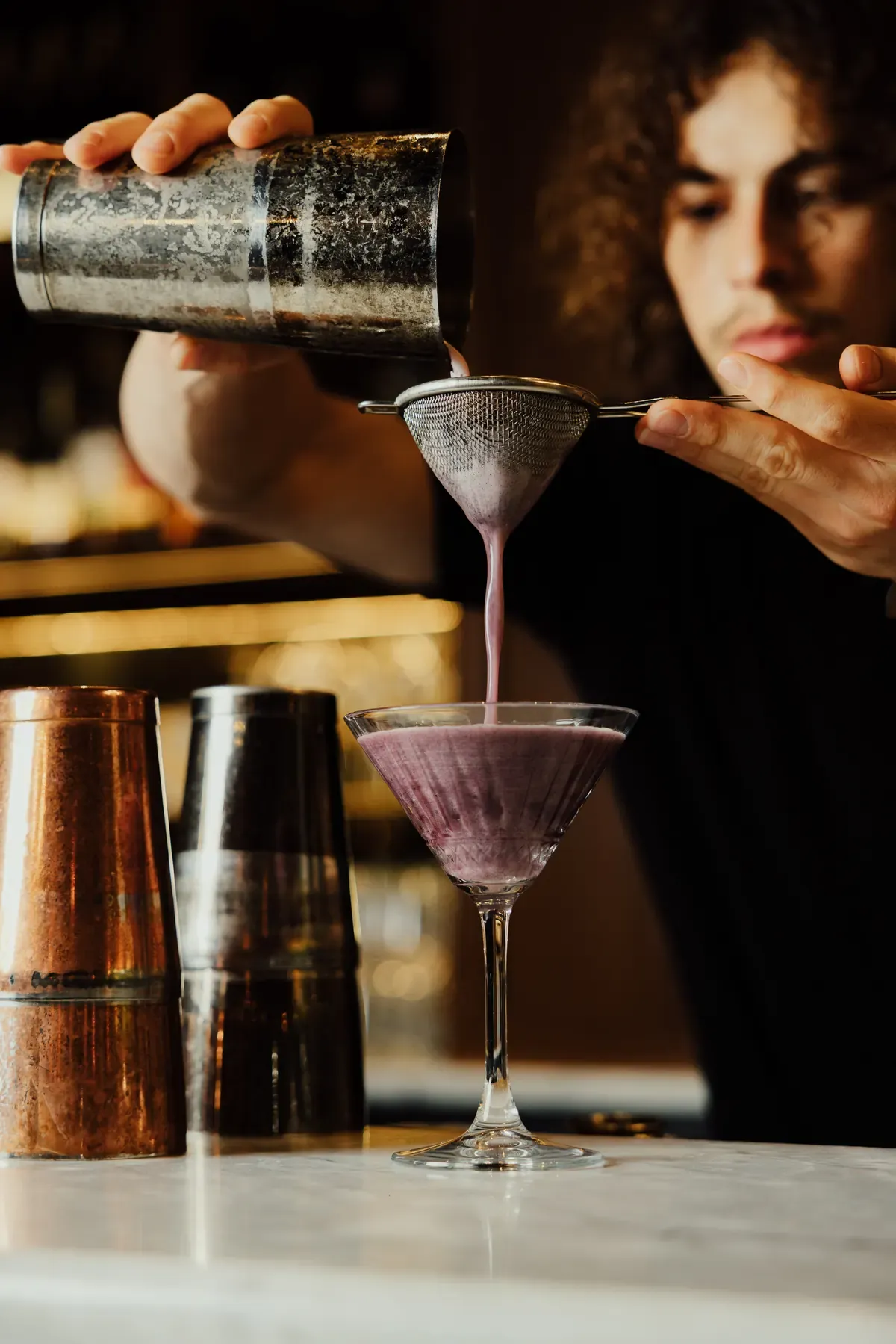 Le Conteur bartender pouring a berry cocktail