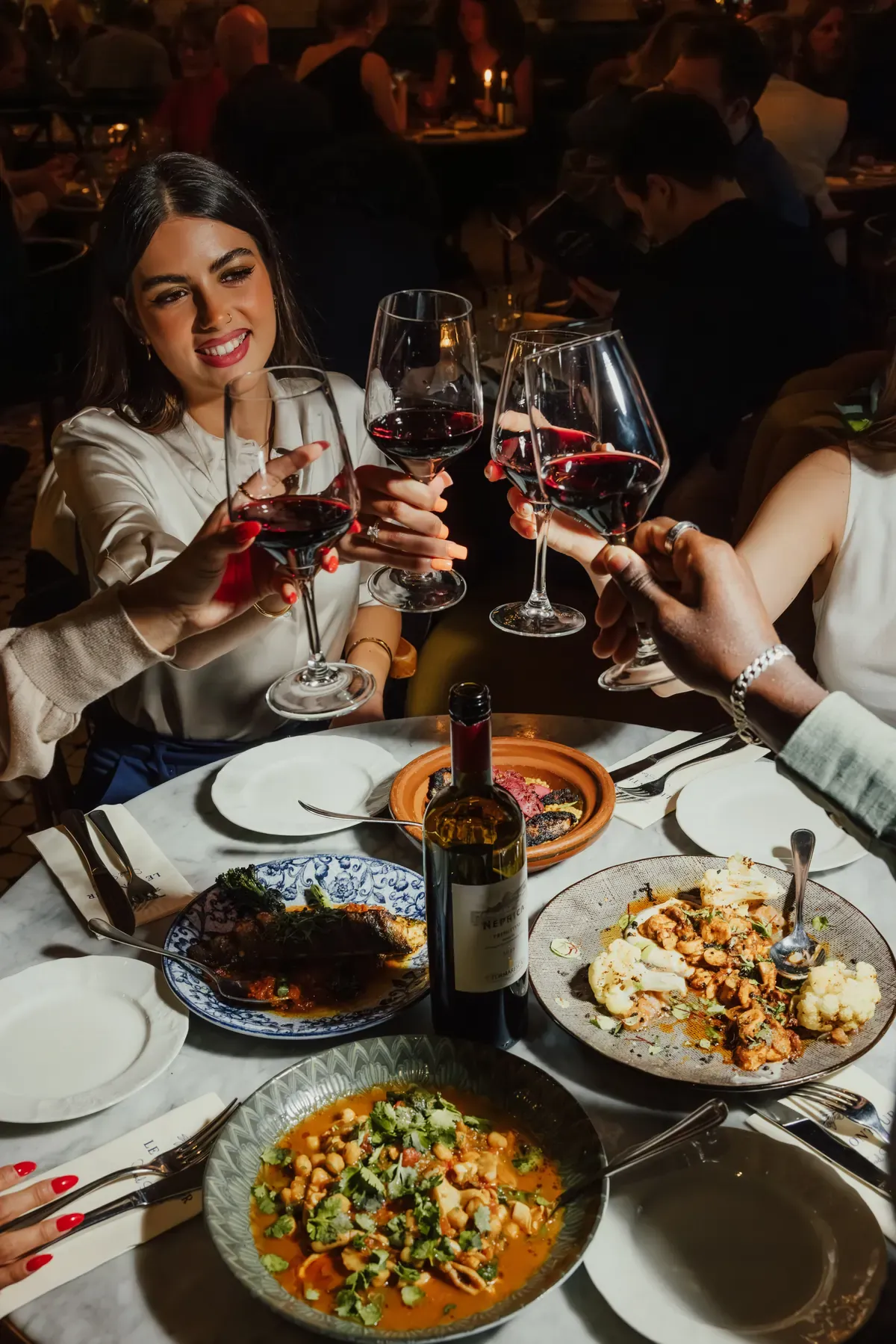 Guests toasting with red wine around a table at Le Conteur